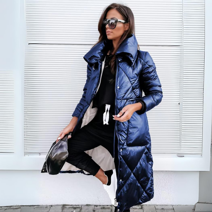 Même manteau long matelassé en bleu marine brillant, porté ouvert par une femme avec lunettes de soleil, sac noir à la main. 3