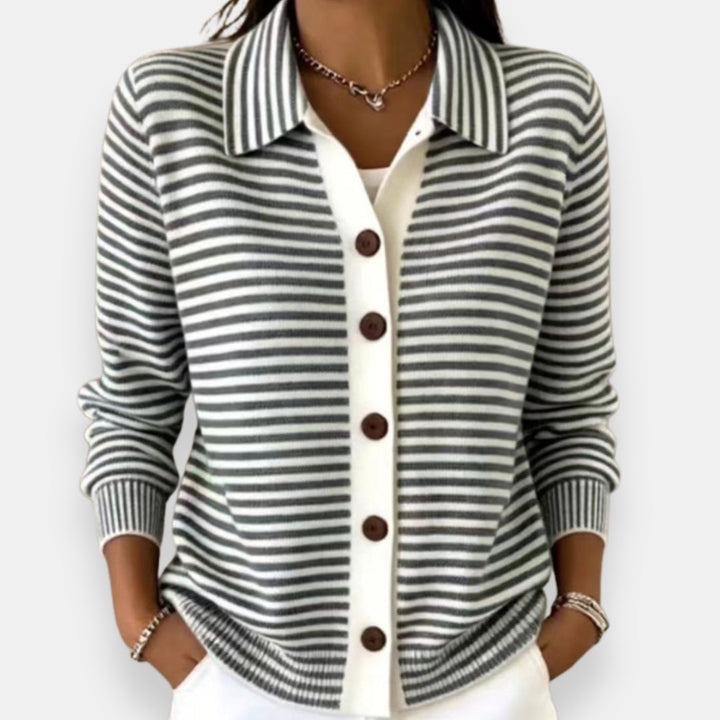 Gilet à rayures grises et blanches porté par une femme, col chemise, boutons marron, poignets côtelés, pantalon blanc. 3