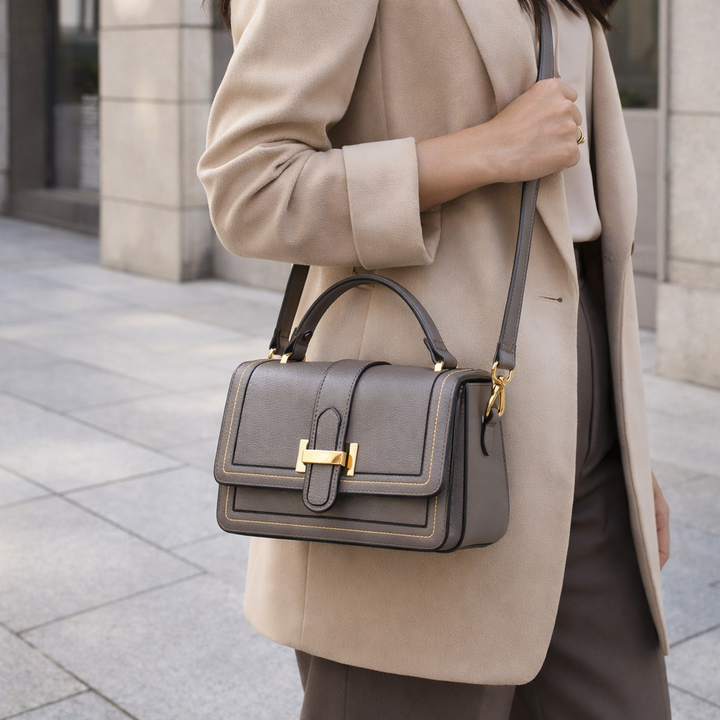 Sac gris taupe porté en bandoulière sur l'épaule par une femme en blazer beige, dans la rue. 4
