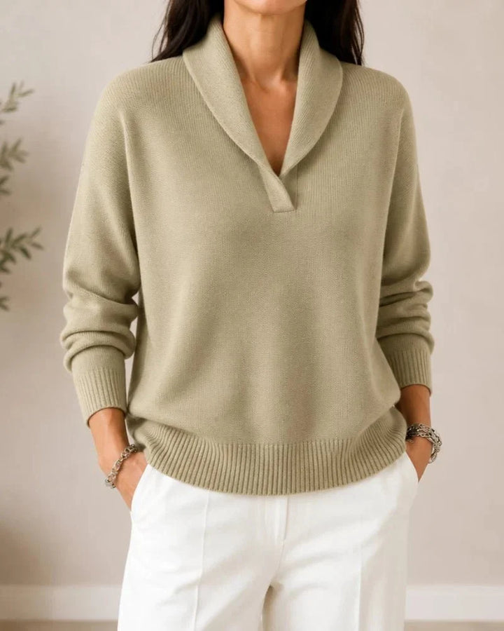 Pull porté de face en coloris beige sable, avec pantalon blanc et mains dans les poches. 9