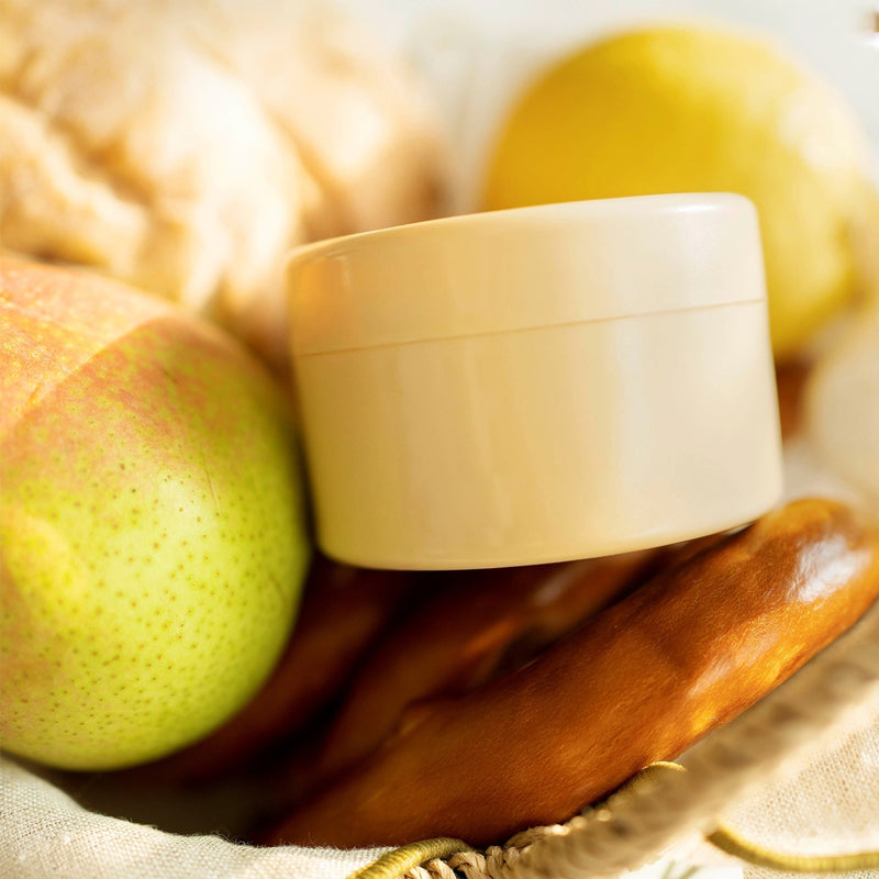 Insert rond de couleur crème posé dans un panier avec une poire, un citron et du pain. 7