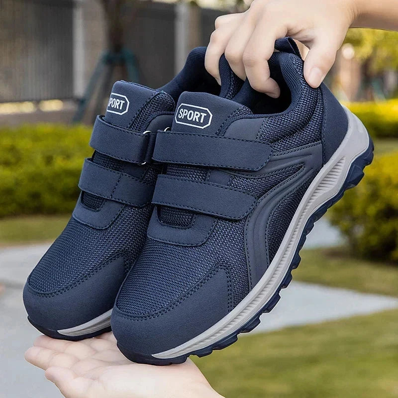 Paire de chaussures bleu marine tenue en main devant un jardin, montrant les deux brides 12