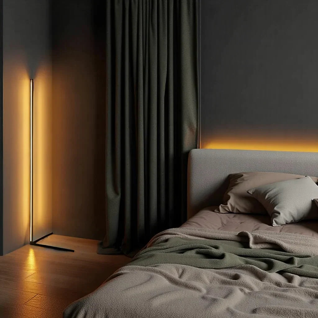 Lampadaire allumé en lumière orangée près d'un rideau vert foncé et d'un lit gris aux coussins 9