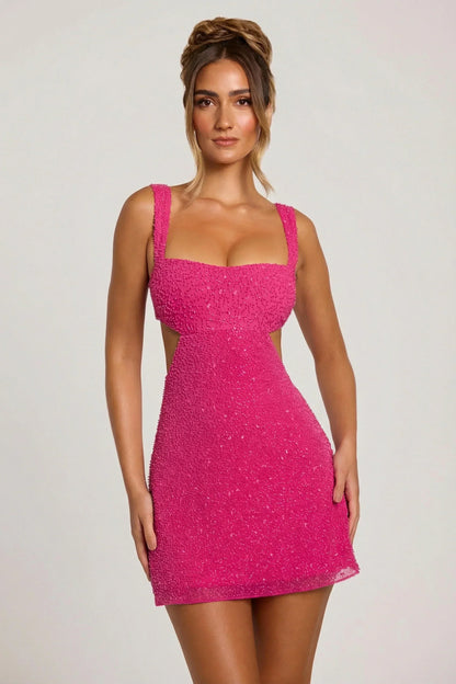 Vue de face de la robe rose fuchsia perlée à larges bretelles et découpes aux flancs, portée par une mannequin. 1