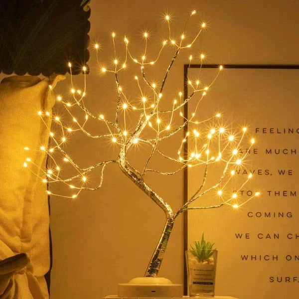 Lampe arbre allumée devant un cadre mural, à côté d'une petite plante grasse et d'un coussin 3