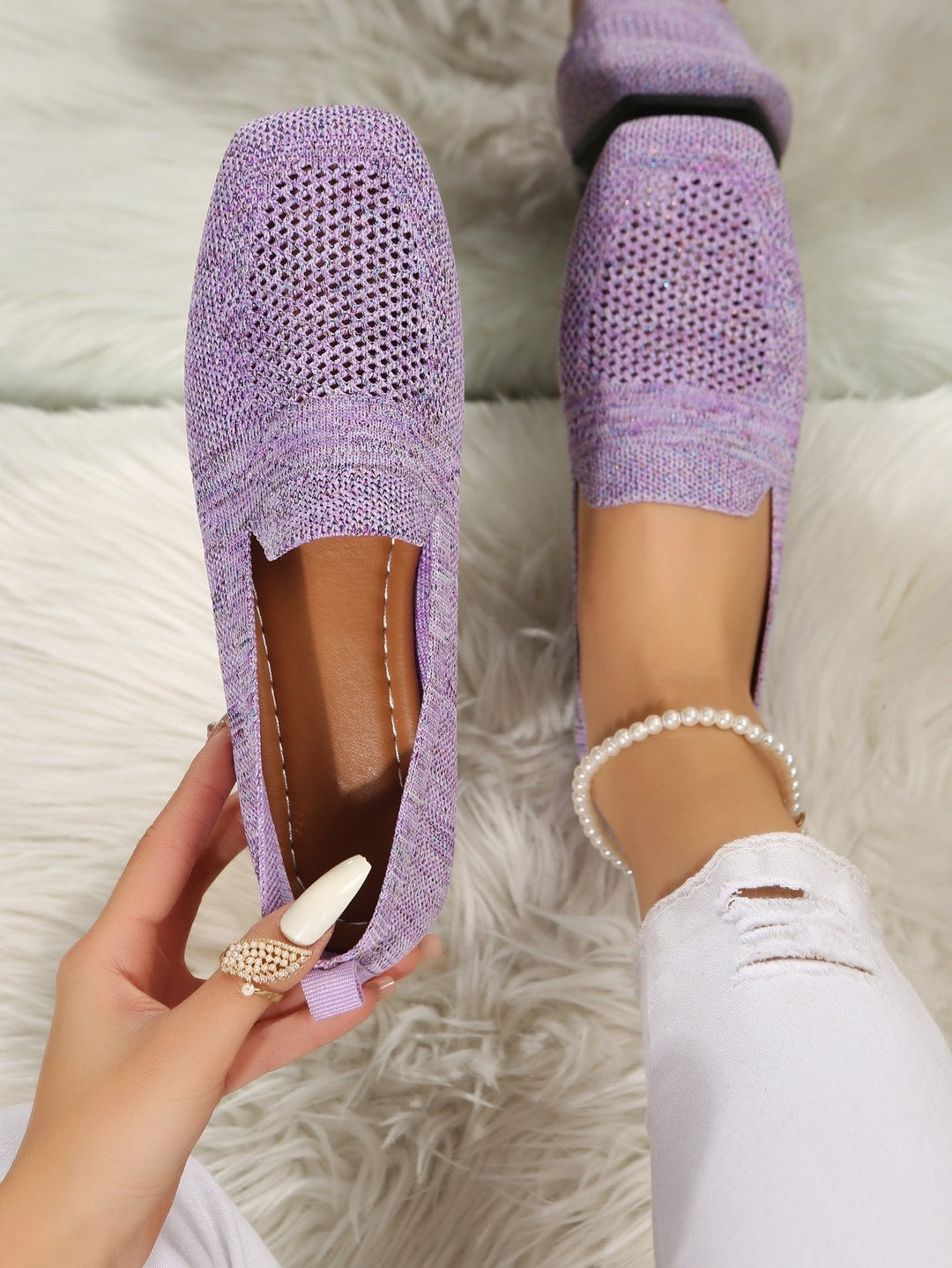 Vue de dessus de la paire violette en mesh, un soulier tenu à la main laissant voir la semelle intérieure marron. 11