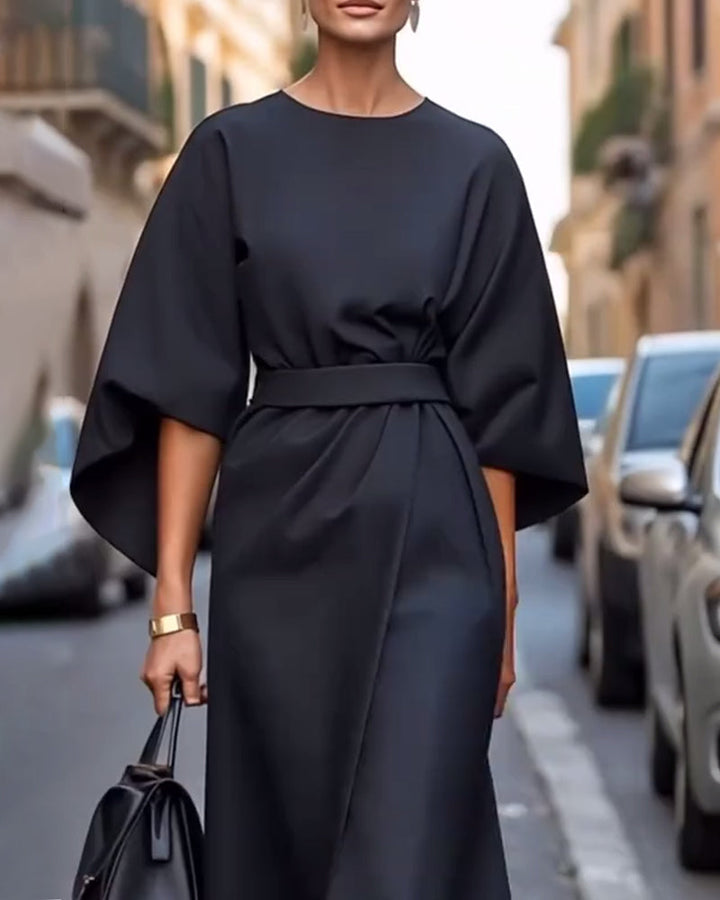 Robe noire à manches lanterne et ceinture nouée à la taille, vue de près avec un bracelet doré et un sac noir. 5