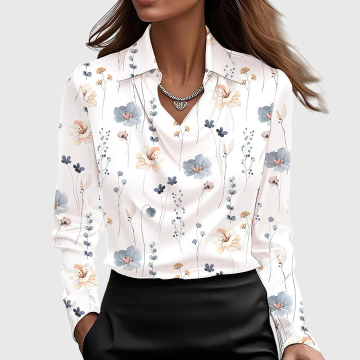 Blouse blanche à col drapé et petites fleurs bleues, roses et orangées imprimées, portée avec une jupe noire. 9