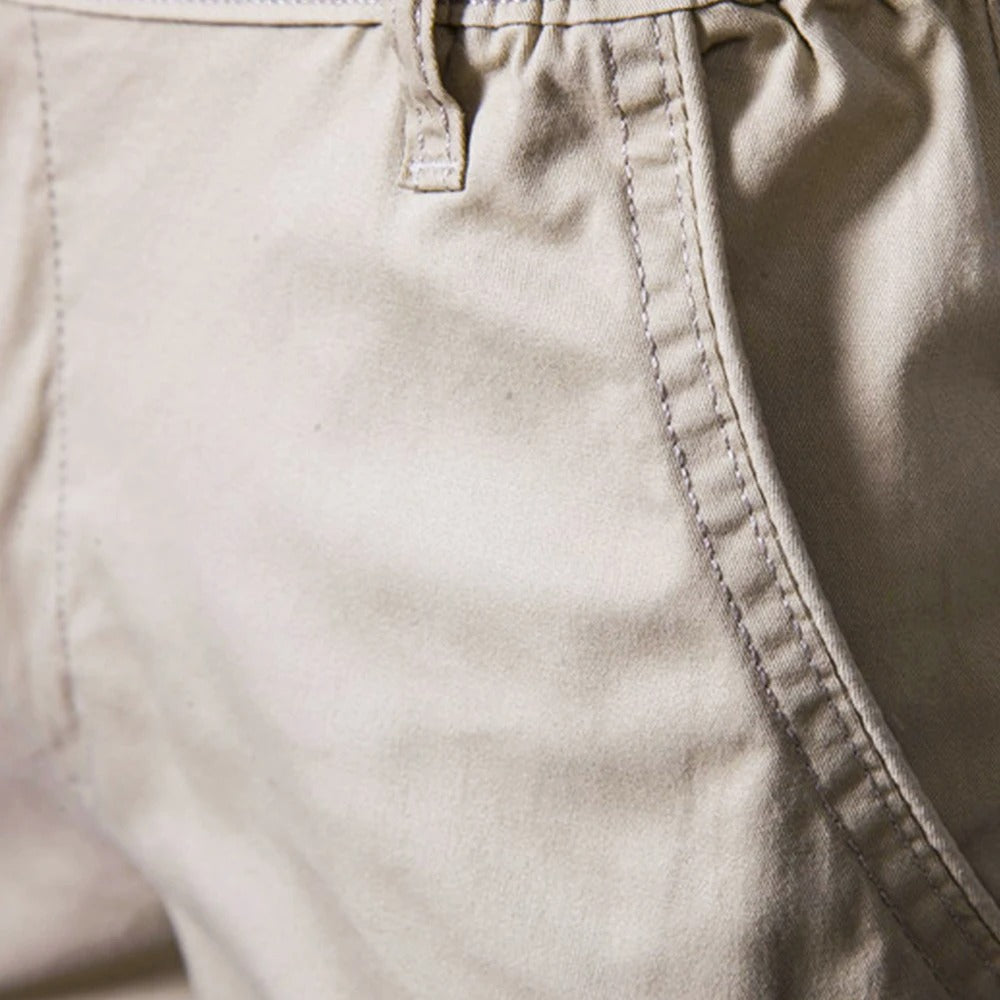 Gros plan sur la poche latérale surpiquée et un passant de ceinture du short beige. 3