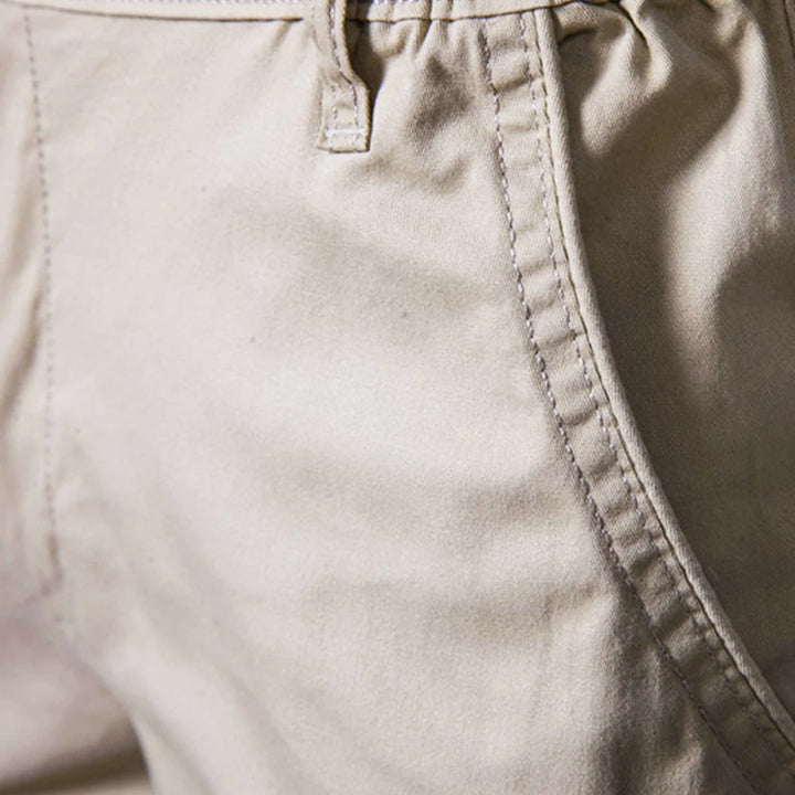 Gros plan sur la poche latérale surpiquée et un passant de ceinture du short beige. 3