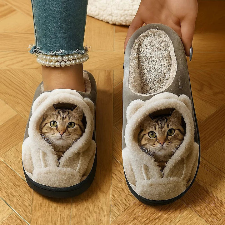 Vue de dessus de chaussons gris portés par une personne, l'un tenu à la main pour montrer sa doublure en fausse fourrure douce. 1