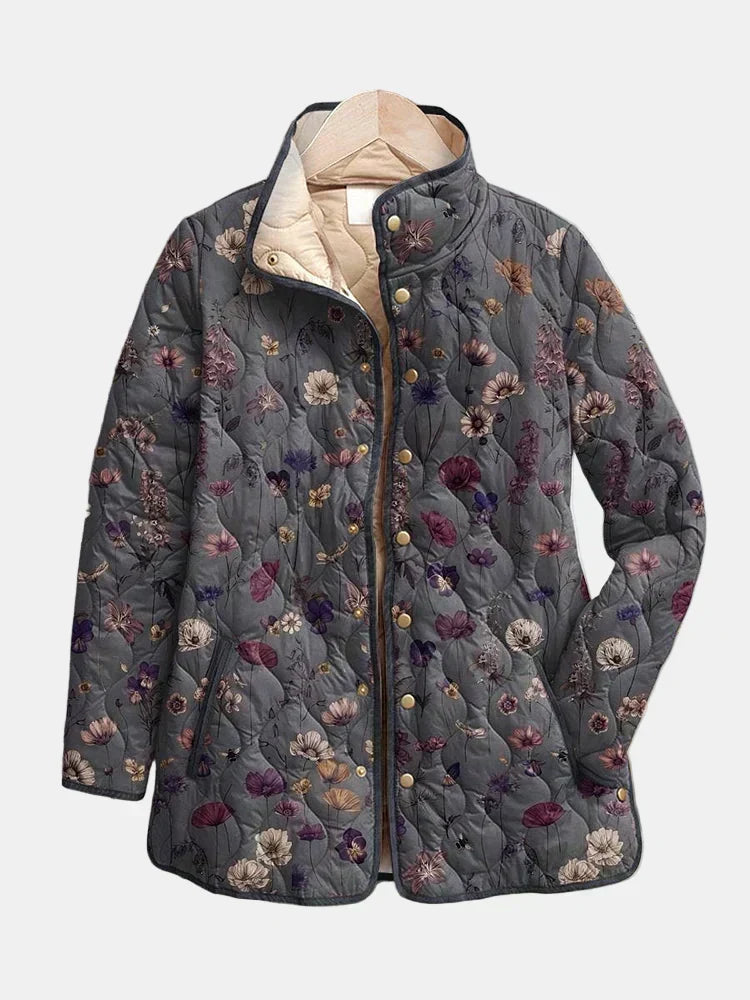 Veste matelassée grise à motif floral présentée sur cintre, fermée par des boutons-pression dorés, avec col montant et doublure beige. 2