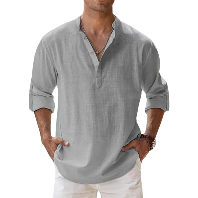 Homme portant la chemise Henley grise, manches retroussées, mains dans les poches d'un pantalon blanc, vue de face. 6