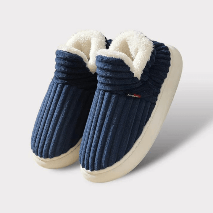 Paire de chaussons bleu marine côtelés à doublure blanche moelleuse et épaisse semelle crème, posée sur fond clair uni. 21