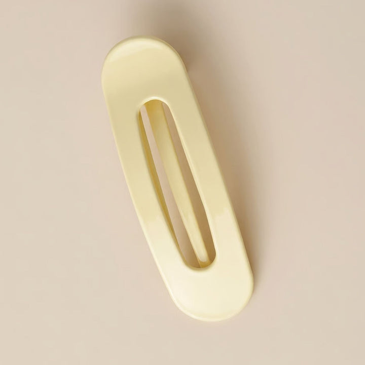 Barrette plate jaune pâle brillante à fente centrale, vue de dessus sur fond beige 6
