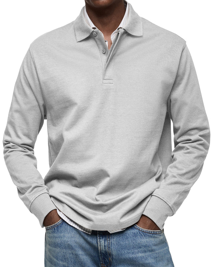 Polo à manches longues gris clair porté par un homme, mains dans les poches, boutons assortis, chemise rayée dessous et jean. 5