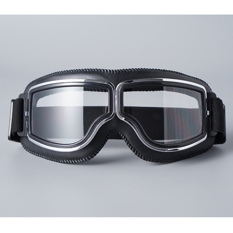 Lunettes à monture chromée et contour en similicuir noir, verres transparents, sangle élastique noire, vues de face sur fond gris. 2
