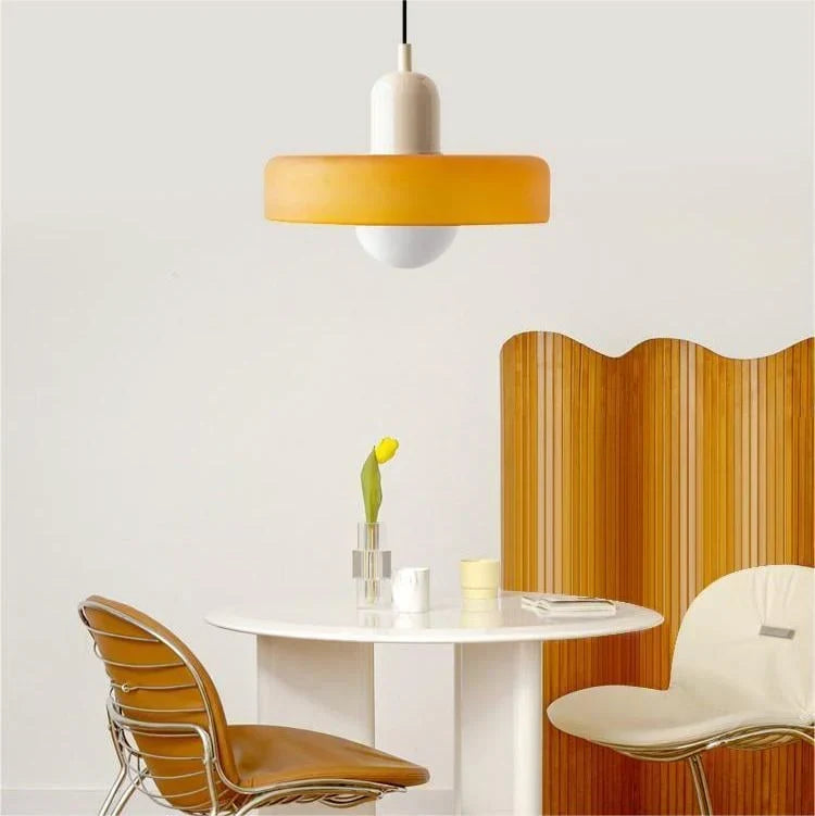 Suspension orange à capuchon crème au-dessus d'une table ronde blanche, avec chaises et paravent en bois ondulé. 11