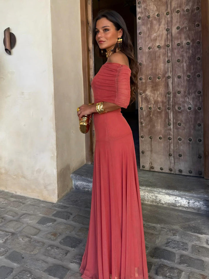 Robe corail à épaules dénudées et manches drapées, vue de profil devant une porte cloutée 6