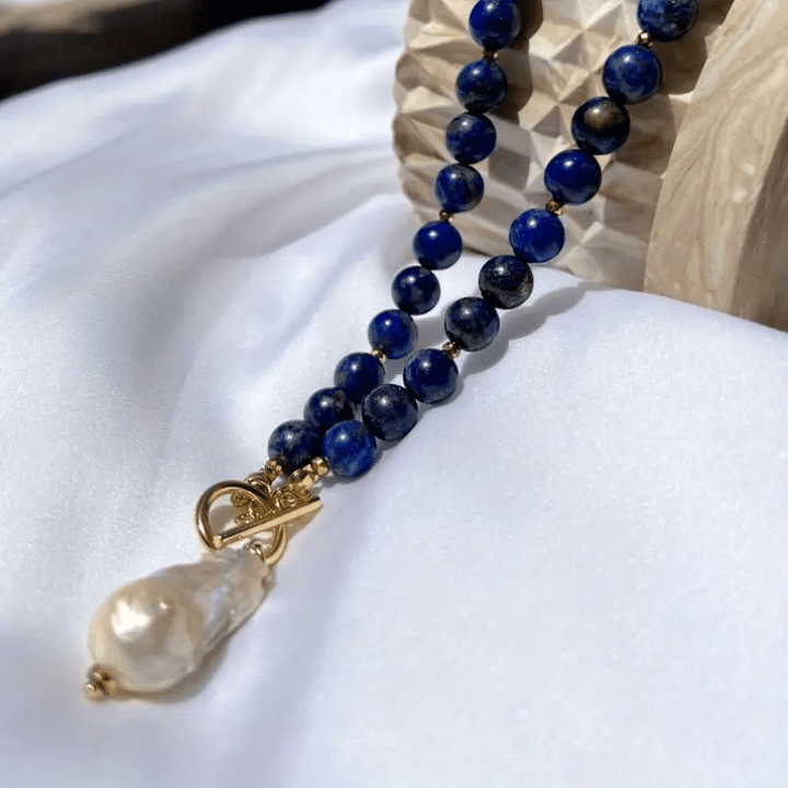 Collier présenté sur un drap blanc contre un objet en bois sculpté, perle baroque pendante 6