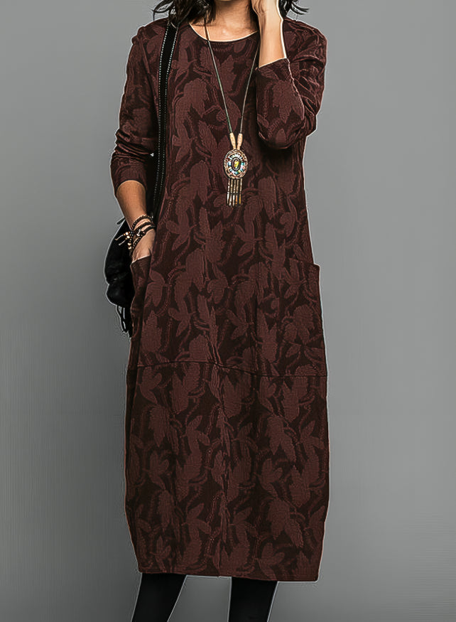 Robe portée par un modèle en bordeaux foncé, avec long collier à pendentif et sac noir 2