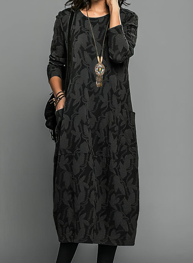 Robe portée par un modèle en noir, avec long collier à pendentif et sac noir 4