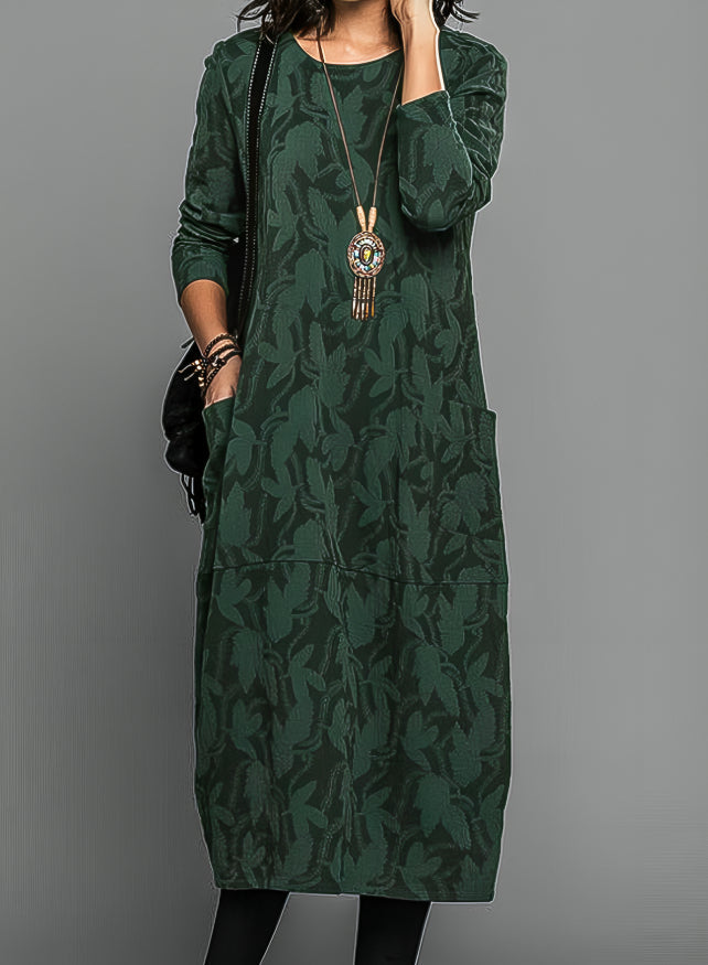 Robe portée par un modèle en vert foncé, avec long collier à pendentif et sac noir 1