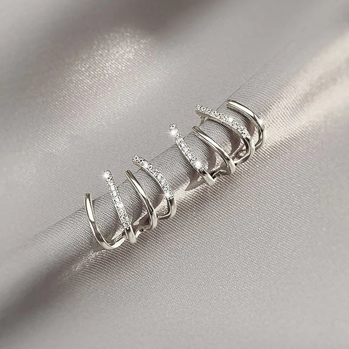Paire de boucles à griffes en version argentée, posée sur un tissu satiné gris 6