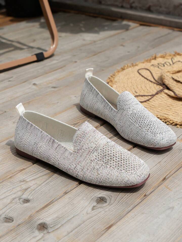 Paire gris clair en maille posée sur un plancher en bois, avec languette de talon et doublure intérieure blanche visibles. 17