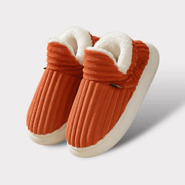 Paire de chaussons orange côtelés avec bord en peluche blanche et semelle crème, présentée sur fond clair. 18