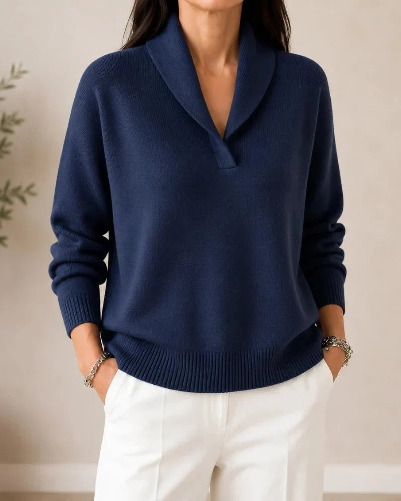 Pull porté de face en coloris bleu marine, avec pantalon blanc et bracelets en métal. 7