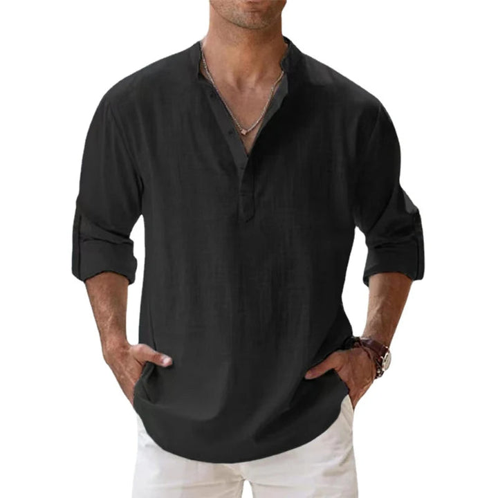 Homme portant la chemise Henley noire, manches retroussées, mains dans les poches d'un pantalon blanc, vue de face. 7
