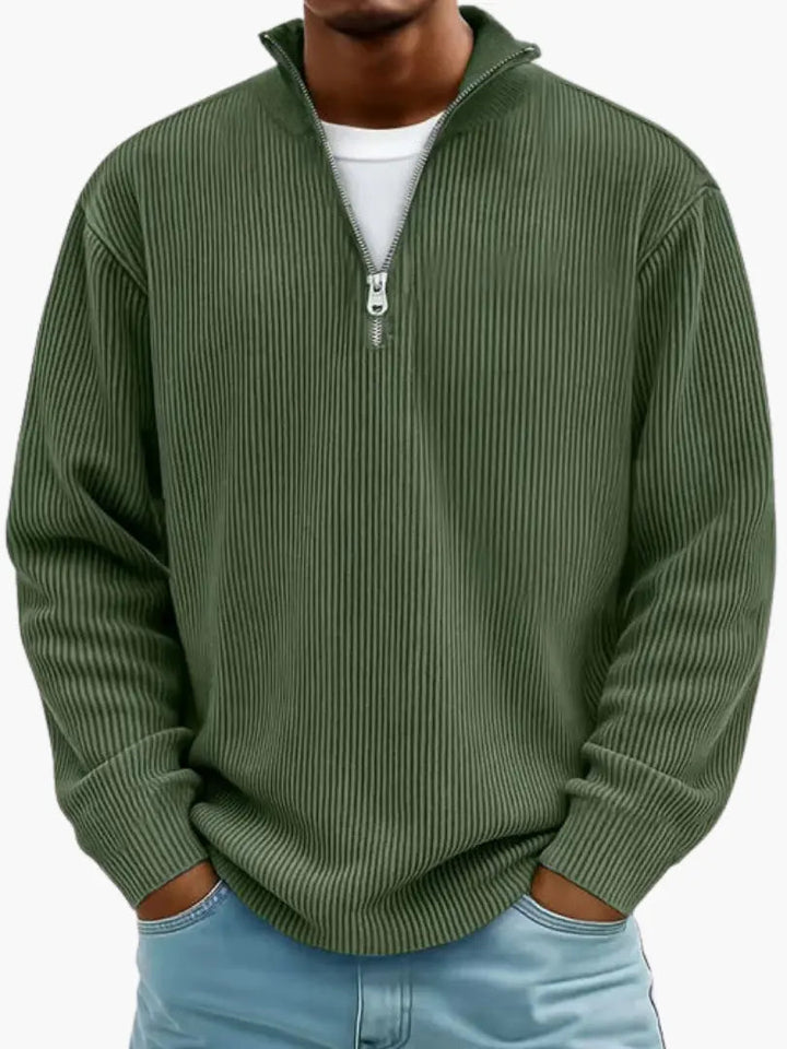 Homme portant le pull côtelé à col zippé en vert kaki, mains dans les poches d'un jean bleu clair. 8