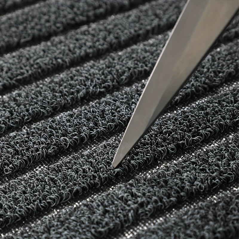 Détail des boucles de fibres du tapis, avec la pointe d'une lame de ciseaux posée entre deux bandes pour montrer leur épaisseur. 5