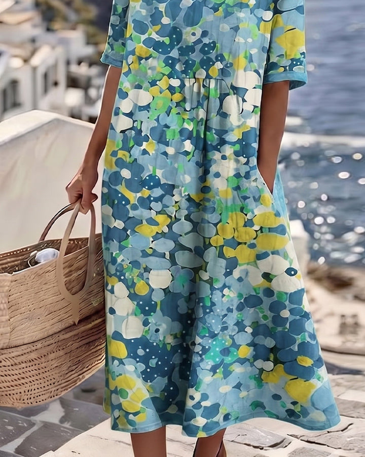Détail de la jupe fluide de la robe bleue à fleurs, avec poche latérale et panier de paille 11