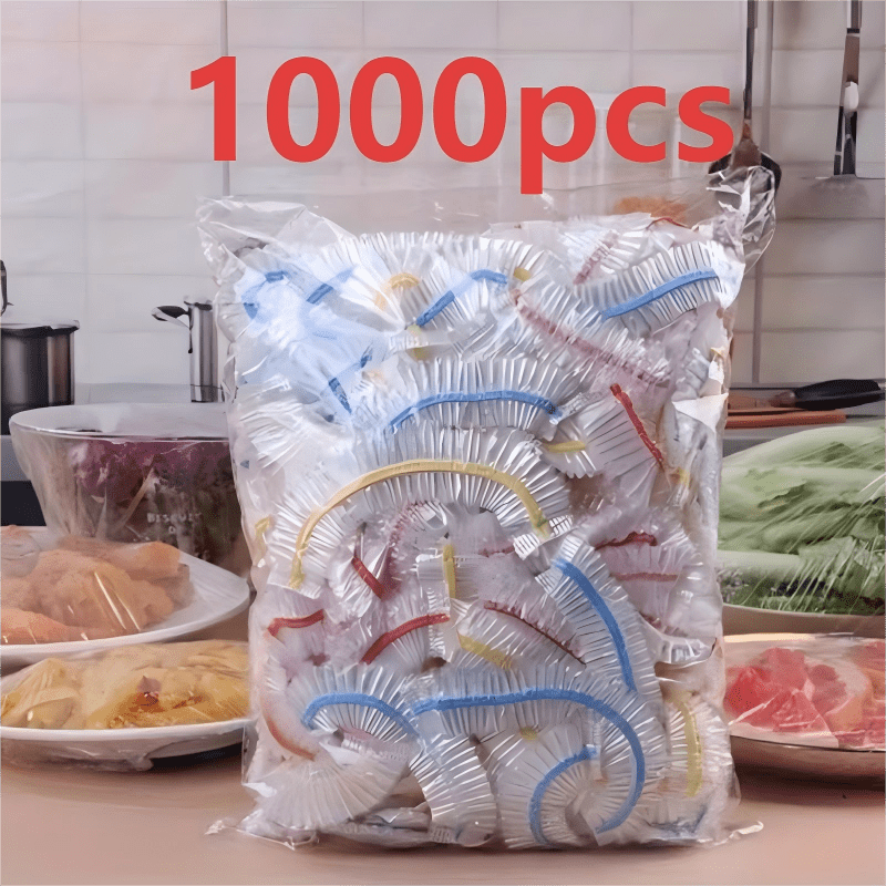Sachet de couvercles élastiques à bandes colorées sur un plan de travail, entouré d'assiettes de viande, de légumes et de pâtes filmées. 3