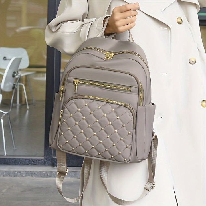 Sac à dos gris-beige tenu par la poignée par une femme en manteau clair 5