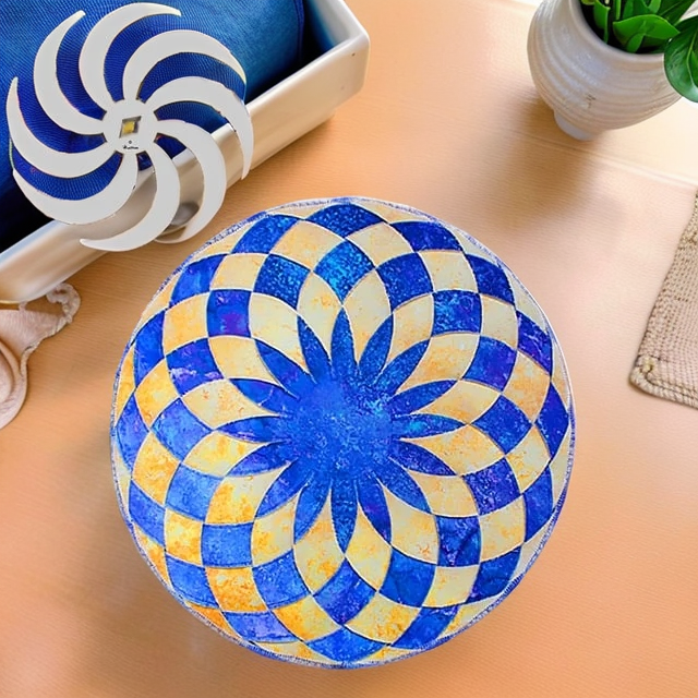 Set de table rond en patchwork bleu et jaune clair sur une table orangée, avec une plante, une corbeille et le gabarit en spirale. 8