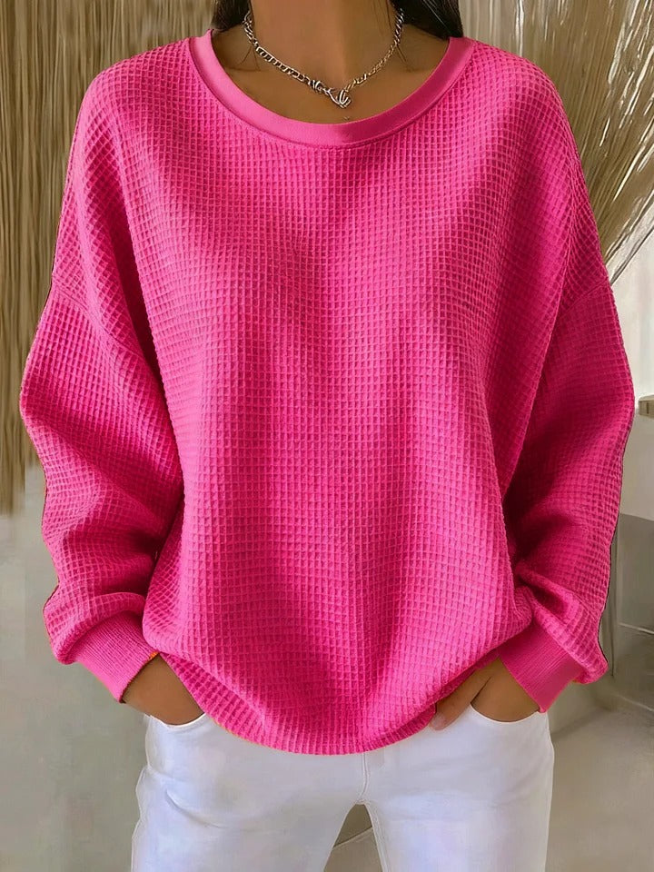 Pull gaufré rose fuchsia à col rond et poignets côtelés, porté par un modèle avec un pantalon blanc. 9