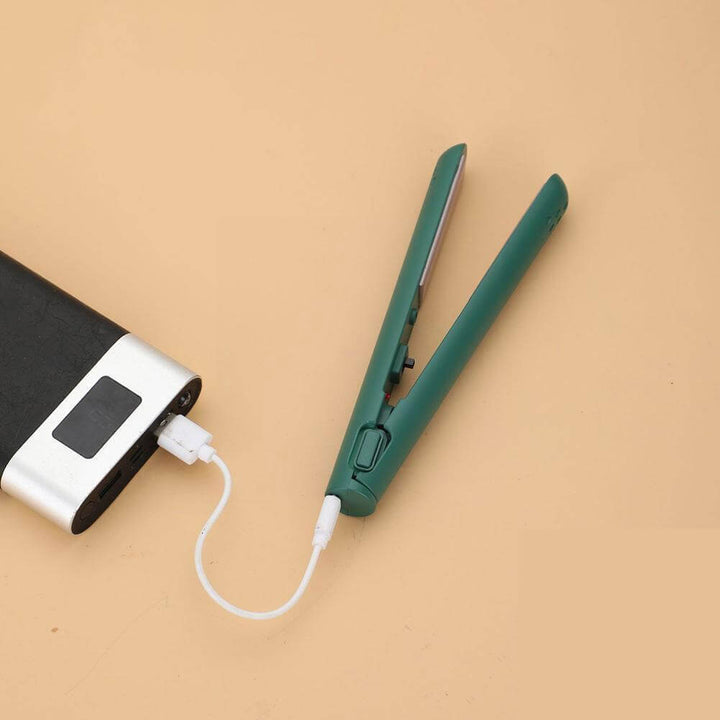 Lisseur vert ouvert, branché par un câble USB blanc sur une batterie externe, posé sur un fond beige. 1