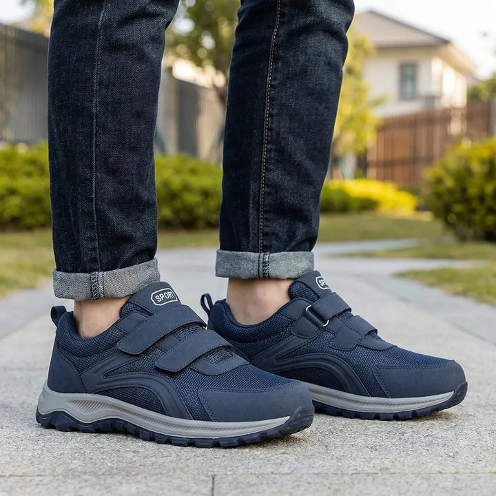 Chaussures bleu marine à deux scratchs portées avec un jean retroussé sur un chemin de parc 1