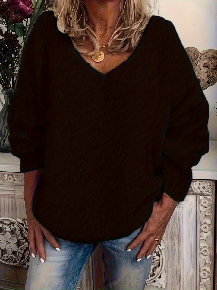 Pull noir à col en V et manches longues, coupe ample, porté avec un jean bleu délavé. 3