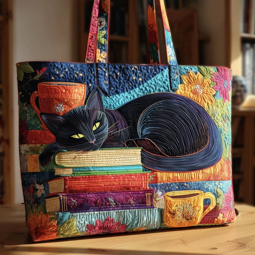 Sac cabas matelassé posé sur une table en bois, motif d'un chat noir endormi sur une pile de livres colorés. 1