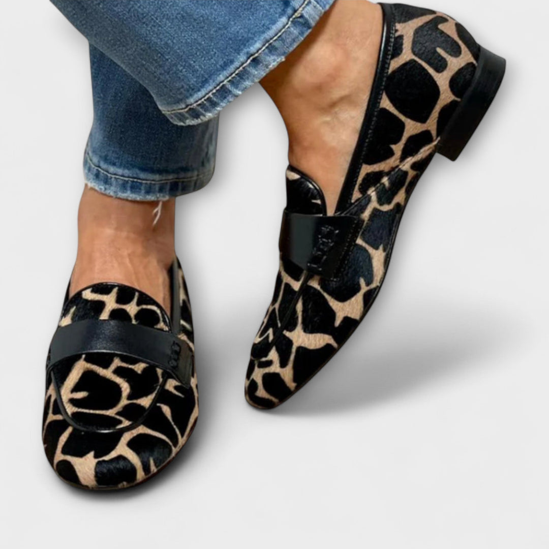 Mocassins imprimé animalier portés par une femme, vus de face et de profil, avec bride noire, liseré noir et petit talon. 3