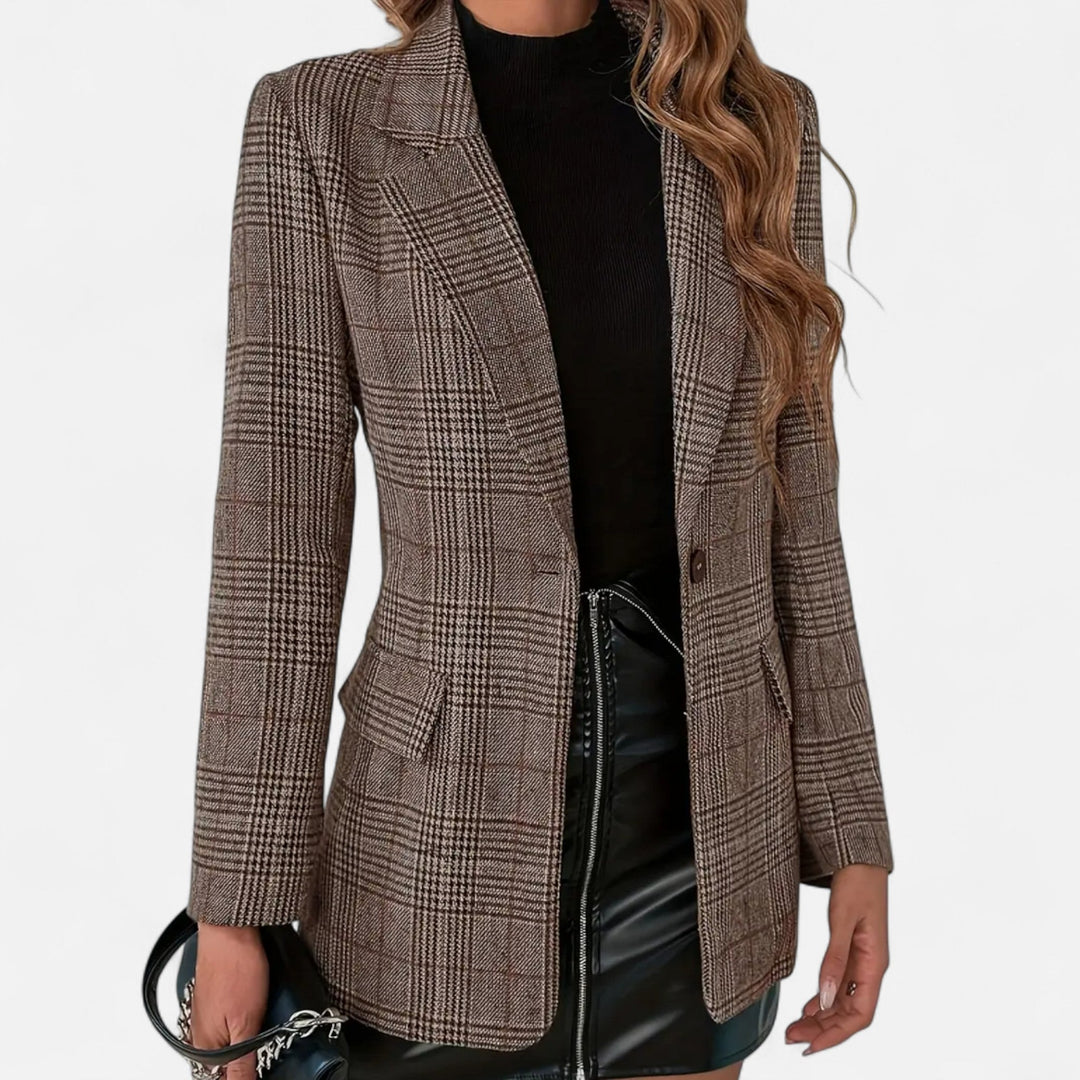 Vue de face rapprochée du blazer à carreaux marron porté ouvert avec un haut noir, une jupe en similicuir et un sac à main. 1