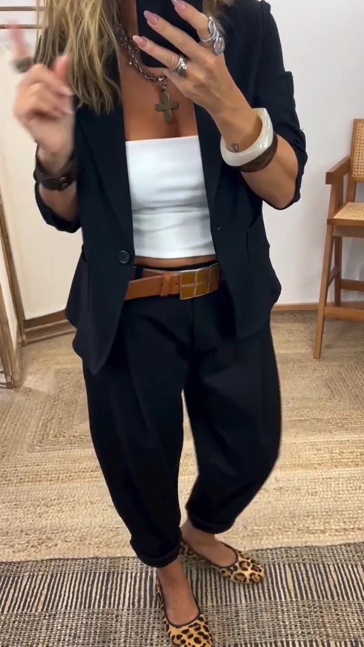 Femme en miroir portant l'ensemble noir, blazer à un bouton et pantalon ample, avec haut blanc et ceinture marron. 3