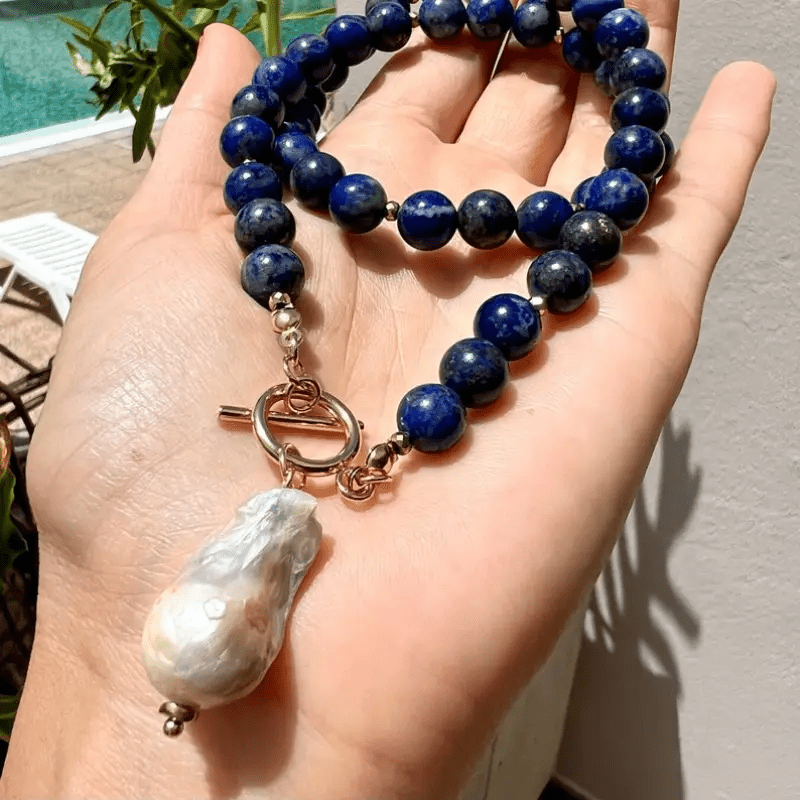 Collier posé dans le creux d'une main, perle baroque pendante et fermoir à bascule dorés en évidence 2