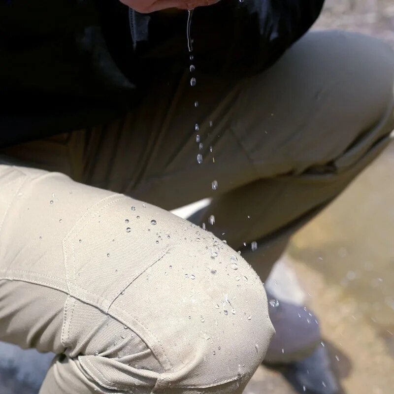 Gros plan sur le genou d'un pantalon beige où l'eau perle en gouttelettes, montrant le tissu déperlant et les coutures renforcées. 7