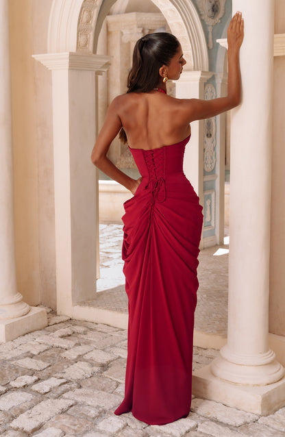 Vue de dos de la robe rouge : lacet croisé du bustier et drapé de la jupe, devant des arcades en pierre. 23