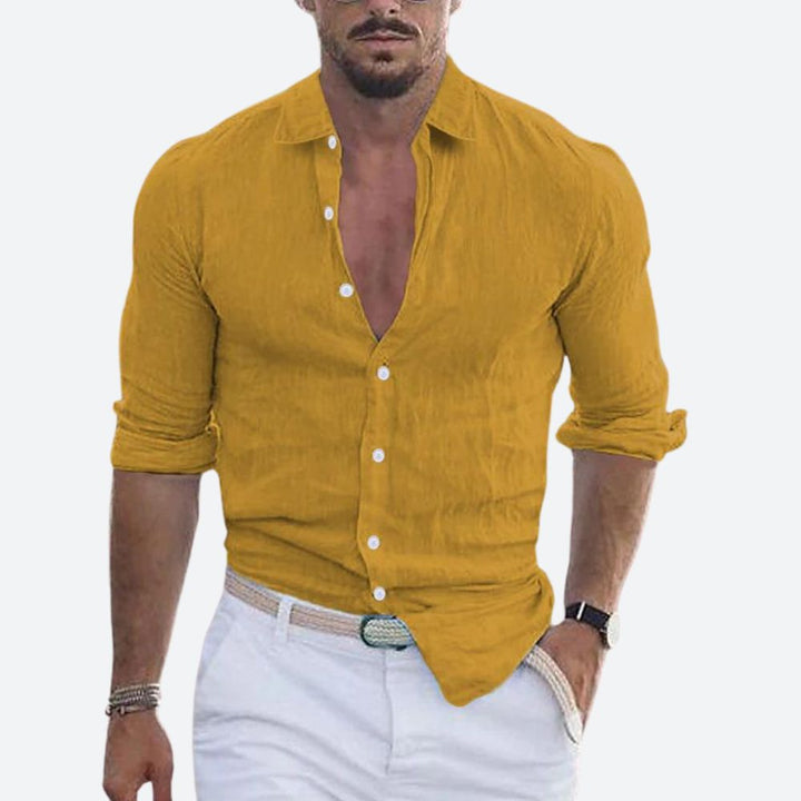 Chemise jaune moutarde portée par un homme, col ouvert, manches retroussées, avec pantalon blanc et ceinture tressée. 2